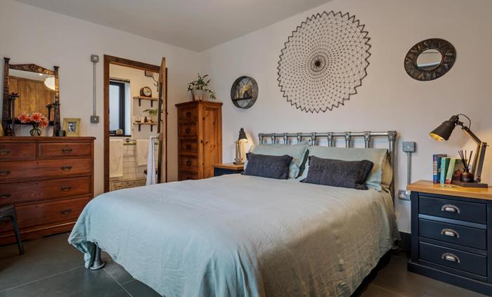 large bedroom with en-suite (shower, basin and w.c.) on the ground floor, chest of drawers, built in wardrobes, bedside cupboards with lamps, smart TV